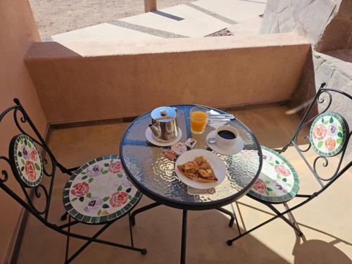 a table with two chairs and a plate of food on it at Hotel Pirwa in San Pedro de Atacama