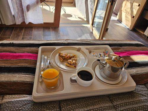 a tray with breakfast foods and coffee on a bed at Hotel Pirwa in San Pedro de Atacama