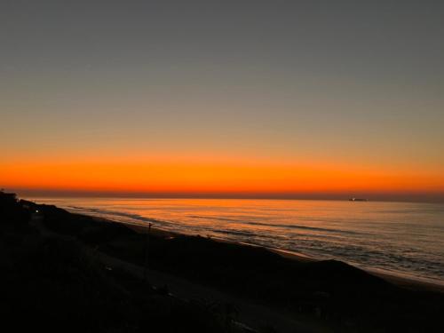 a sunset over the ocean at the beach at Low Tide in Densainagar