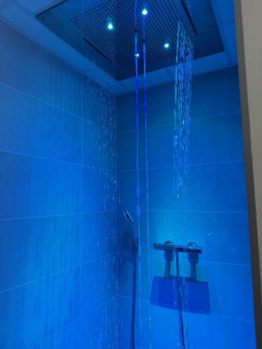 La salle de bains bleue est pourvue d'une douche avec des lumières bleues. dans l'établissement Kyriad Saumur Hyper Centre Hôtel, Appartements, Séminaires et SPA soins Sothys Paris, à Saumur