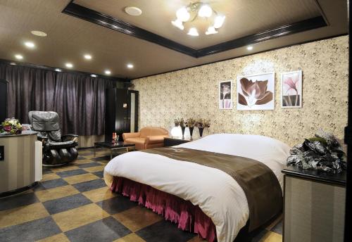 a bedroom with a large bed and a chair at Kashiba Hotel Flower Style (Adult Only) in Kashiba