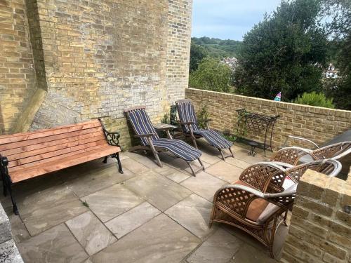 a group of chairs and a wooden bench on a patio at Croft House Apartments in Hastings