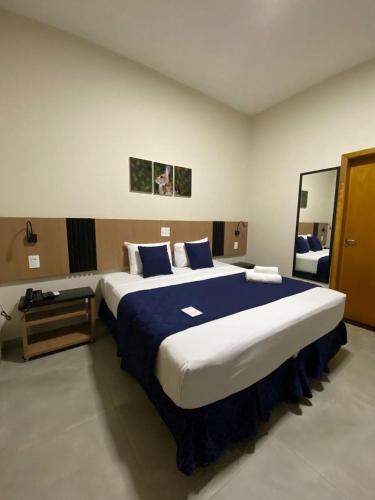 a bedroom with a large bed with blue and white sheets at Visionsul Hotel in Chapadão do Sul