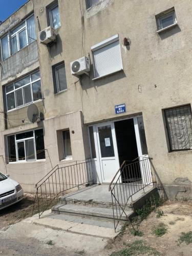 un bâtiment avec une porte blanche et une voiture garée à l'extérieur dans l'établissement Apartamentul lui Vlad, à Jurilovca