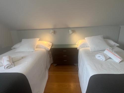 two beds in a room with white sheets and towels at Cerca de Santander La Llosa de Muriedas en Urbanización in Camargo