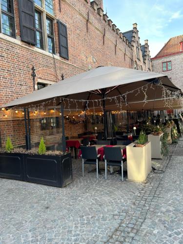 a restaurant with tables and chairs under a large umbrella at De Bijenkorf in Damme