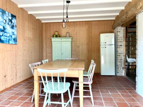 a kitchen with a wooden table and chairs and a refrigerator at De Scheure, charmant vakantiehuisje midden in de natuur in Alveringem