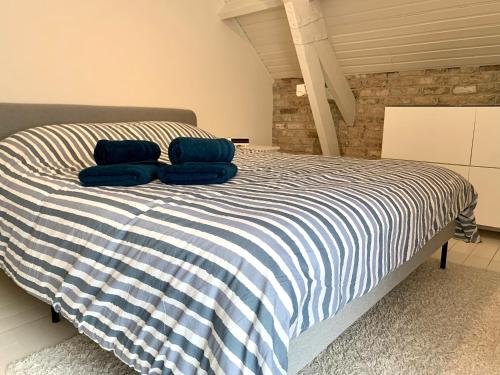 a bed with two blue pillows on top of it at De Scheure, charmant vakantiehuisje midden in de natuur in Alveringem