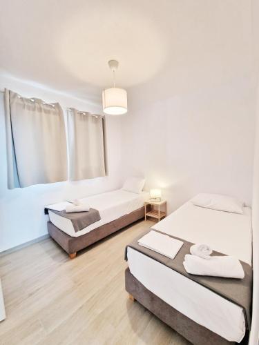 two beds in a room with white walls and wooden floors at LOUTRA VILLAS in Agia Paraskevi
