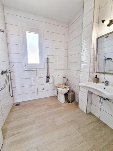 a white bathroom with a toilet and a sink at LOUTRA VILLAS in Agia Paraskevi