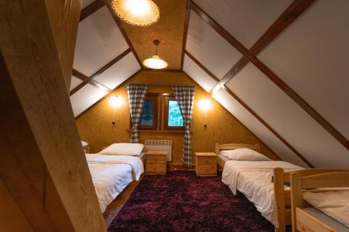 a attic room with two beds and a window at Między Sosnami in Jedwabno