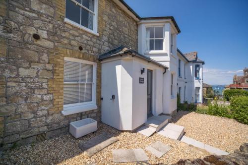 a brick house with a white door and a building at Jumble Cottage in Seaview