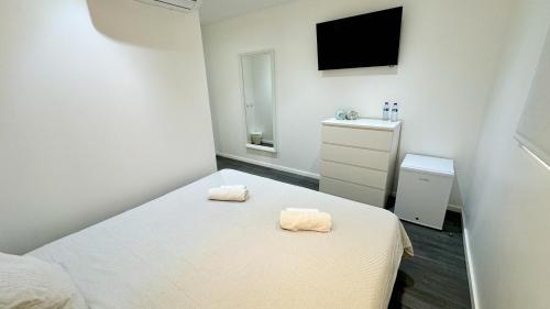a white bedroom with two towels on a bed at Casa Amarela Guesthouse in Albufeira