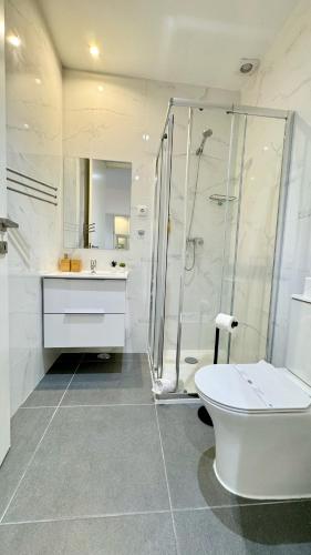 a white bathroom with a shower and a toilet at Casa Amarela Guesthouse in Albufeira