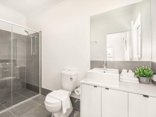 a white bathroom with a toilet and a shower at Modern Family Retreat in Premier GreenbankLocation in Springfield Lakes