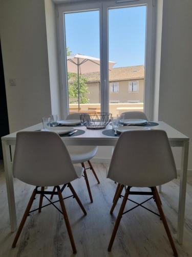une table à manger blanche avec deux chaises et une fenêtre dans l'établissement Maison de village avec terrasse, à Grans
