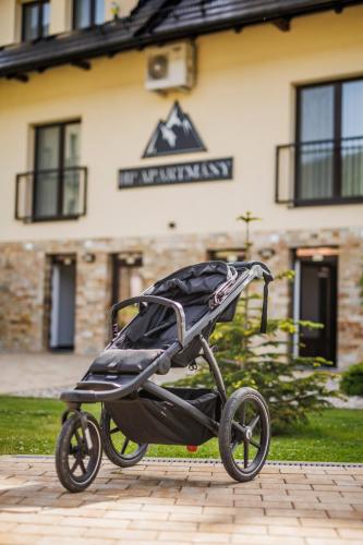 a black stroller sitting in front of a building at HP APARTMÁNY SKIAREÁL- Buková Hora v Orlických horách 100 m od lanovky in Červená Voda