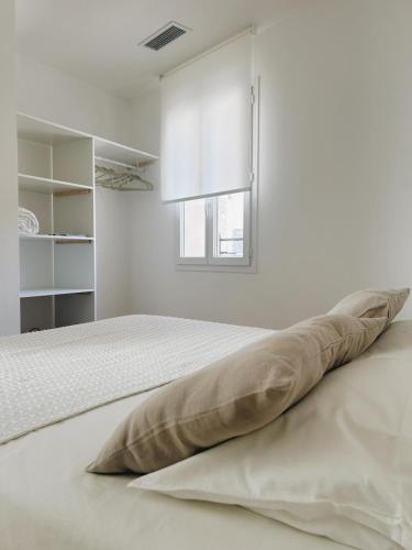 une chambre blanche avec un lit et une fenêtre dans l'établissement La Paca Majuca, à Saint-Thibéry