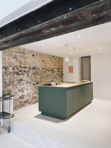 une cuisine avec un mur en pierre et un comptoir dans l'établissement La Paca Majuca, à Saint-Thibéry