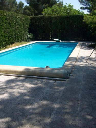 une piscine bleue avec un tuyau dans une cour dans l'établissement Les Cèdres, aux Angles (Gard)