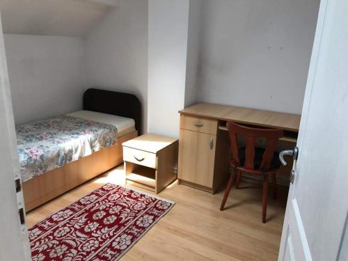 a small bedroom with a bed and a desk and a chair at Taploca Apartman in Topliţa-Ciuc