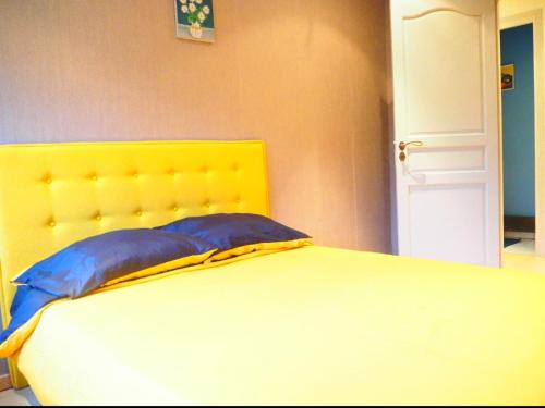 un lit avec une tête de lit jaune et un oreiller bleu dans l'établissement Charmant Appartement au Pecq - Proche de Saint-Germain-en-Laye, à Le Pecq