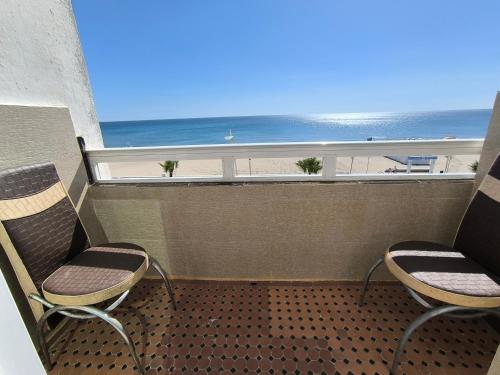 a balcony with two chairs and a view of the beach at Appartement Spacieux et Accueillant avec Vue Panoramique sur la Mer in Martil