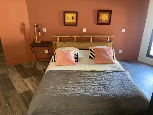 une chambre avec un grand lit avec des oreillers roses dans l'établissement Studio au pied du Luberon, à Caumont-sur-Durance