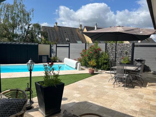 - une terrasse avec une table et un parasol à côté de la piscine dans l'établissement Élégante maison circuit des 24h00 du mans, au Mans