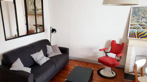- un salon avec un canapé noir et un fauteuil rouge dans l'établissement Dormir à la Rochelle 2 - 50m2 - 1 chambre, à La Rochelle