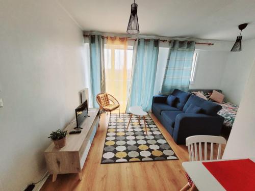 un salon avec un canapé bleu et une télévision dans l'établissement Charmant Studio avec Vue sur l'Orge, Proche RER et Aéroport d'Orly, à Savigny-sur-Orge