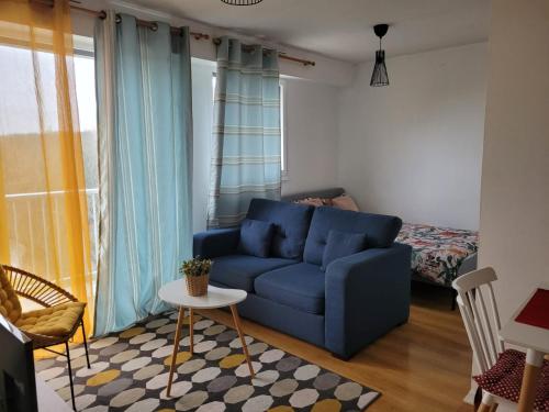 un salon avec un canapé bleu et une table dans l'établissement Charmant Studio avec Vue sur l'Orge, Proche RER et Aéroport d'Orly, à Savigny-sur-Orge