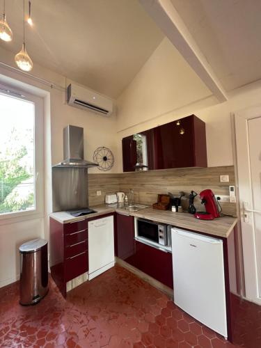 d'une cuisine avec des placards rouges, un évier et une fenêtre. dans l'établissement MAGNIFIQUE DUPLEXE calme et climatisé, à 2 pas d'intra muros, à Avignon