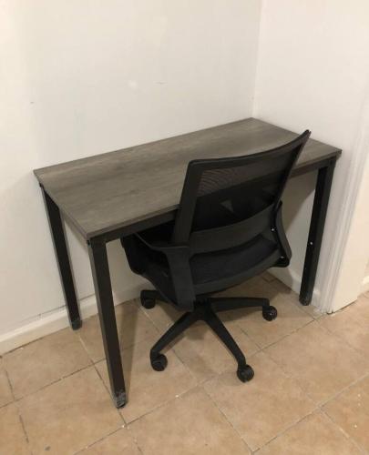 a black desk with a black chair and a wooden desk at Private 3 bedroom and 1 bathroom house, direct NYC Manhattan train a 15 minute walk away, MetLife Stadium FIFA World Cup 35 minutes away in Perth Amboy