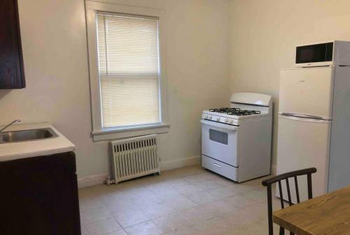 a kitchen with a white stove and a refrigerator at Spacious and bright 2 bedroom apartment with 1 bathroom and private street entrance in Paterson