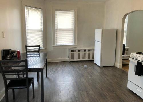 a kitchen with a table and a white refrigerator at Spacious 2 bedroom apartment with 1 bathroom and private street entrance in Paterson