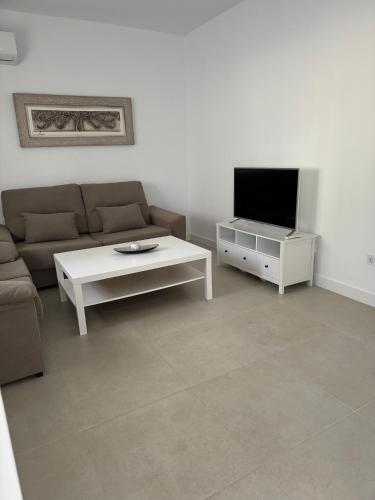 a living room with a couch and a table and a tv at Alojamiento Baeza California 2A in Baeza