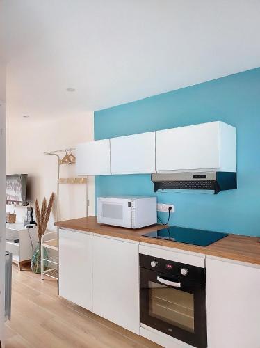 une cuisine avec des armoires blanches et un micro-ondes dans l'établissement L'oasis d'Anatole, à Oyonnax