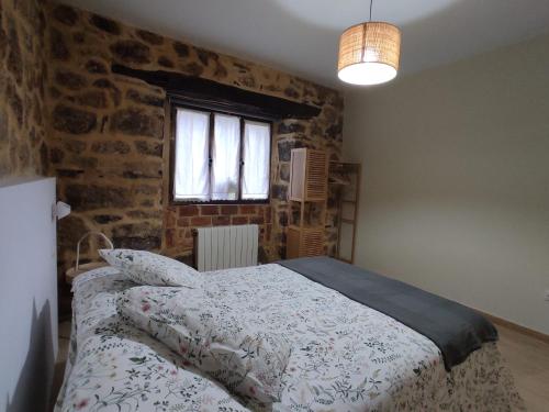 a bedroom with a bed and a brick wall at La casita de Mena in Hoz de Mena