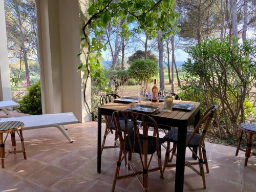 une table et des chaises en bois dans un patio avec une fenêtre dans l'établissement Gîte Confortable Vue Exceptionnelle - Golf de Saumane, à Saumane-de-Vaucluse