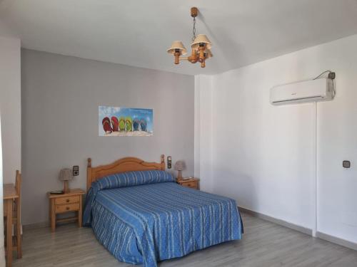een slaapkamer met een bed met een blauwe deken bij Hostal Calaverde in Villaricos