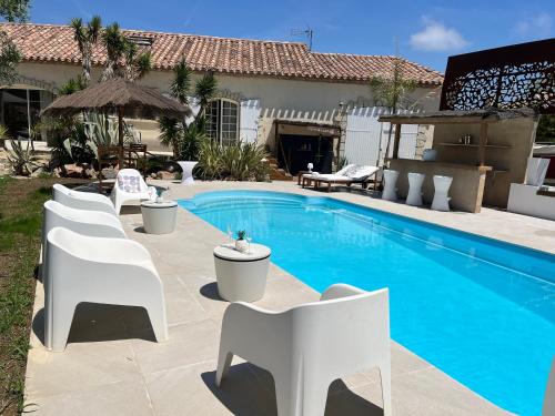- une piscine avec des chaises blanches à côté d'une maison dans l'établissement Lescale, à Sigean