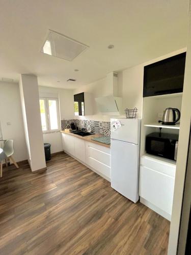 a kitchen with white appliances and wooden floors at GM GÎTE maison neuve et tout confort in Lucey