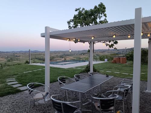 a picnic table and chairs under a pergola at Villa Luxury Vista Vigneti-Piscina Privata in Agliano Terme