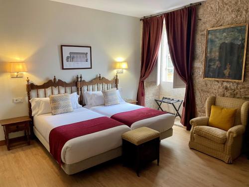 a bedroom with a large bed and a chair at Hotel Pazo de Bieite in Boimorto