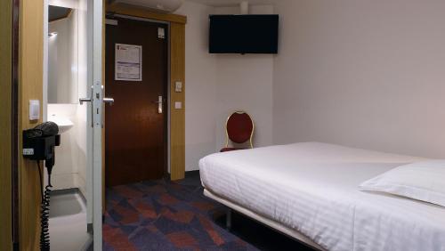 a bedroom with a bed and a television on the wall at In Hotel Nancy Frouard in Frouard