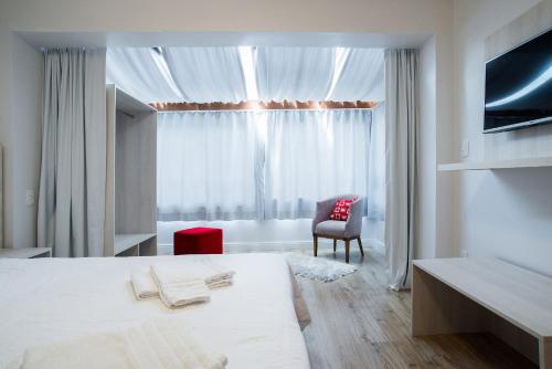 a bedroom with a bed and a chair and a window at Apartamentos Monte Felice Stay in Gramado