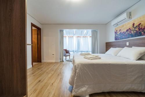 a bedroom with a large white bed in a room at Apartamentos Monte Felice Stay in Gramado