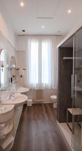 a bathroom with two sinks and a shower and a toilet at Hotel Villa Stucky in Mogliano Veneto