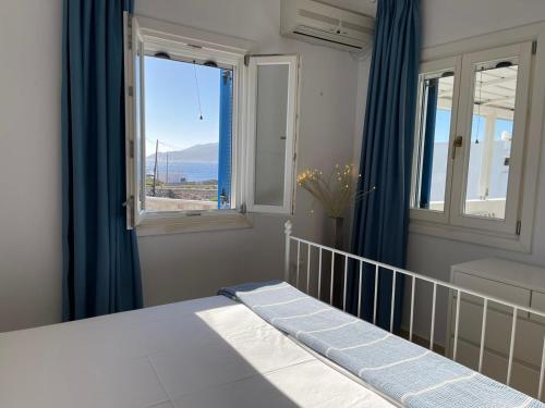 a bedroom with a bed with blue curtains and a window at Karras House in Kimolos